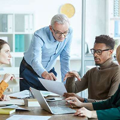 Group of business people pointing at business contract and discussing its details together at the table at meeting at office