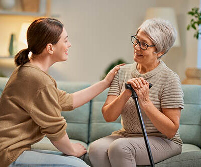 Elderly patient and caregiver spending time together. Senior woman holding cane.